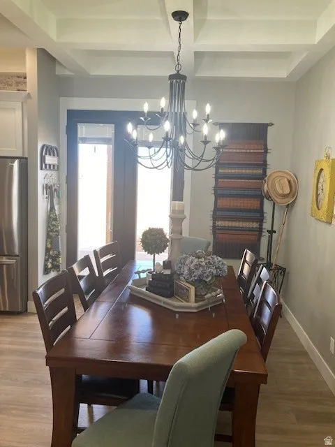 Dining area with wood finished floors, coffered ceiling, and hanging lights