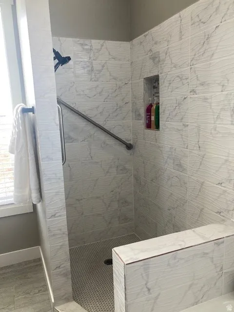 Full master bathroom featuring tiled shower and baseboards