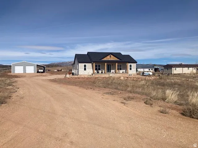 Modern farmhouse style home featuring an outbuilding, a garage, a porch, dirt driveway, and a mountain view