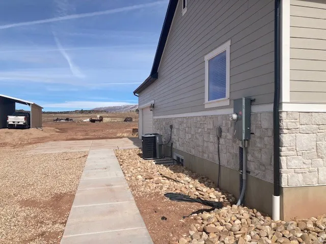 View of side of home featuring stone siding, a garage, and a mountain view