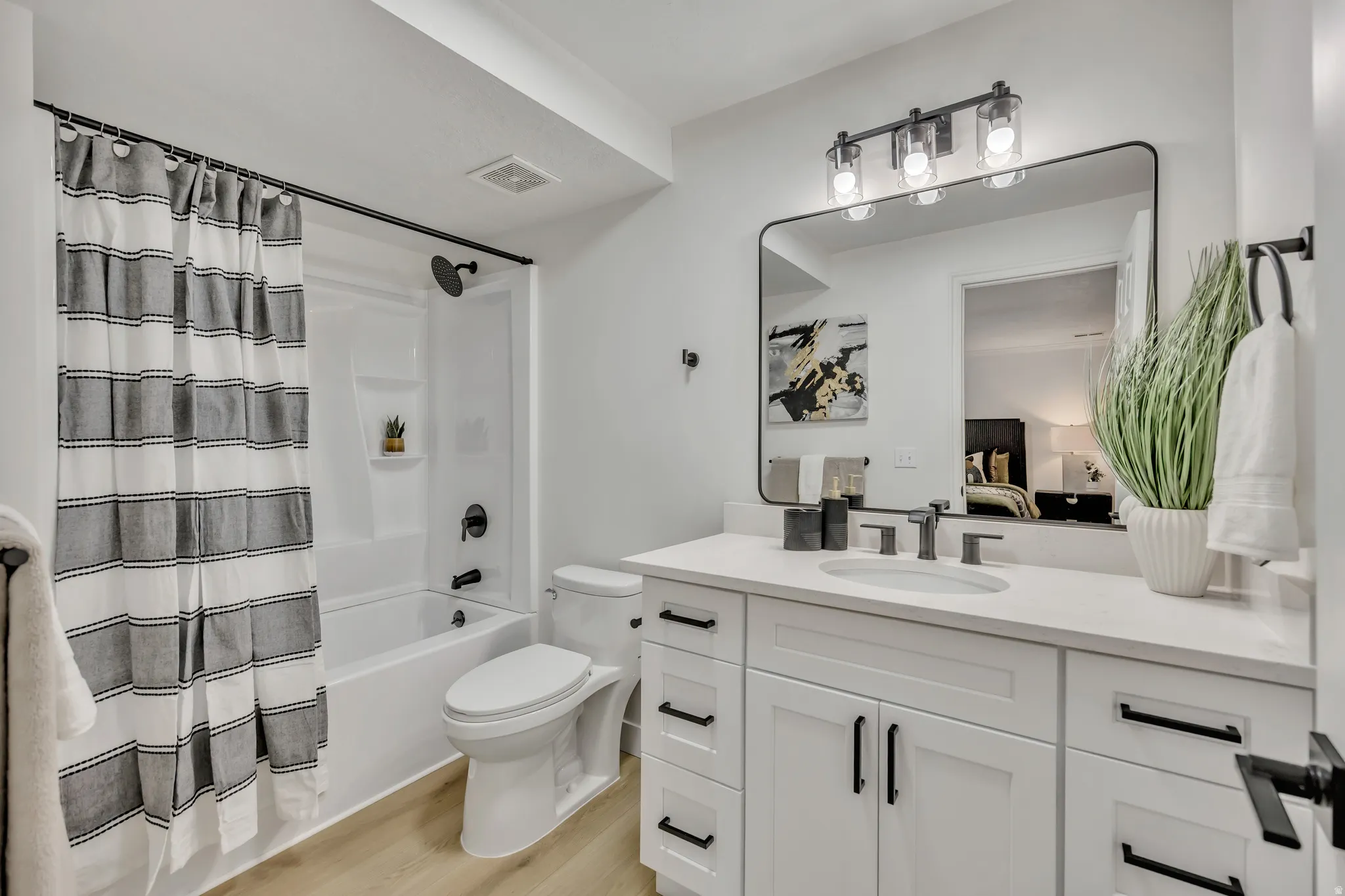 Full bath featuring vanity, connected bathroom, shower / tub combo with curtain, and light wood-style flooring