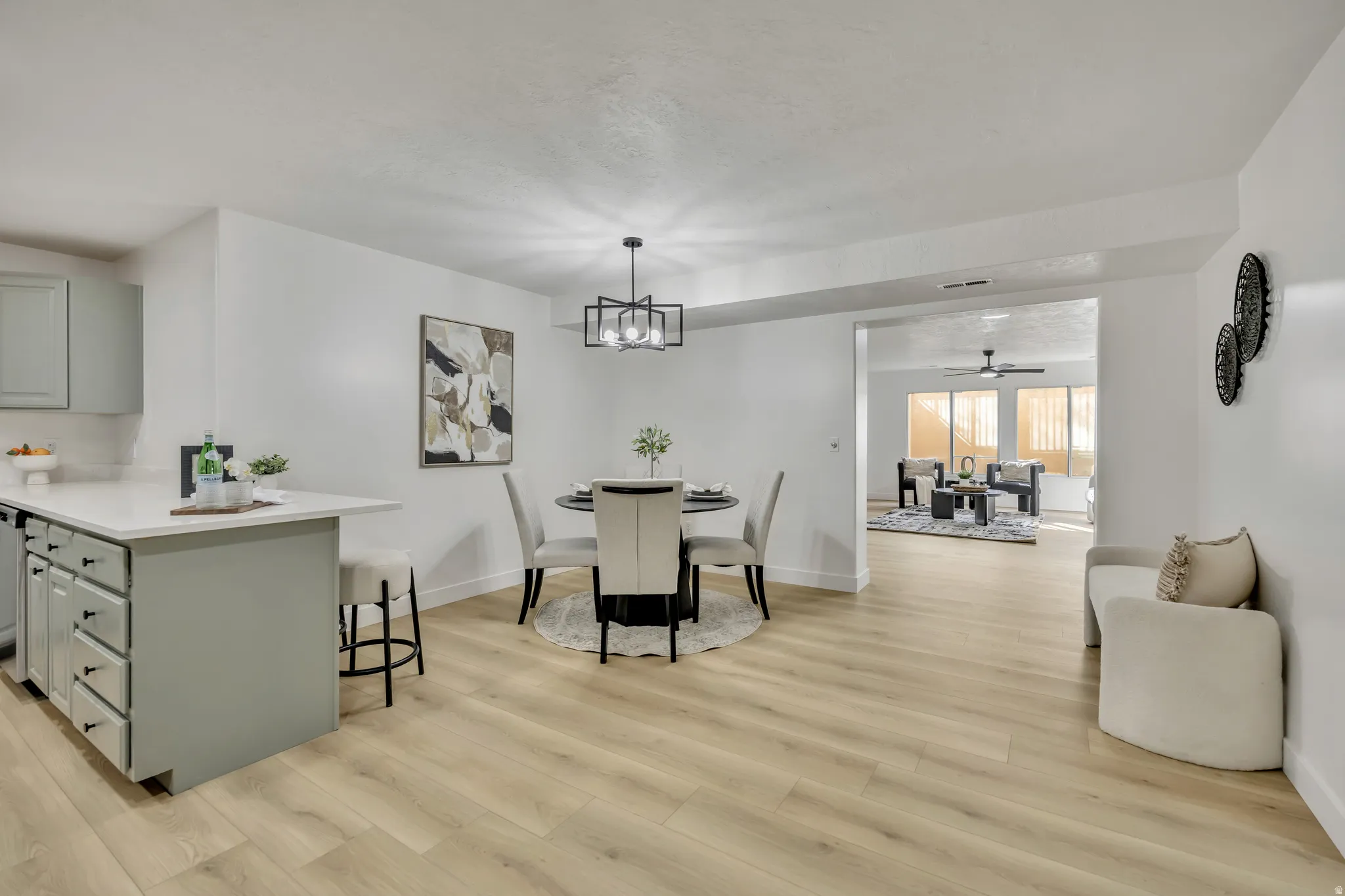 Dining area with a ceiling fan, light wood finished floors, and a chandelier