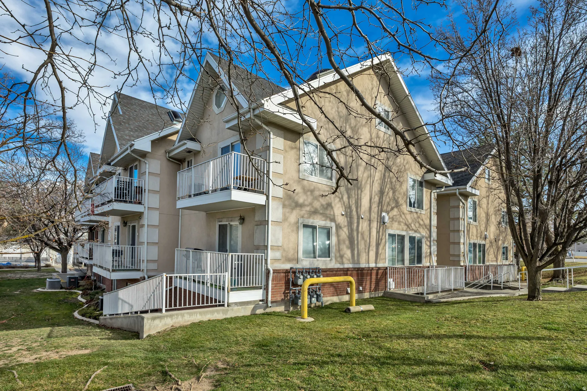 View of home's exterior featuring a balcony, stucco siding, a lawn, roof with shingles, and brick siding