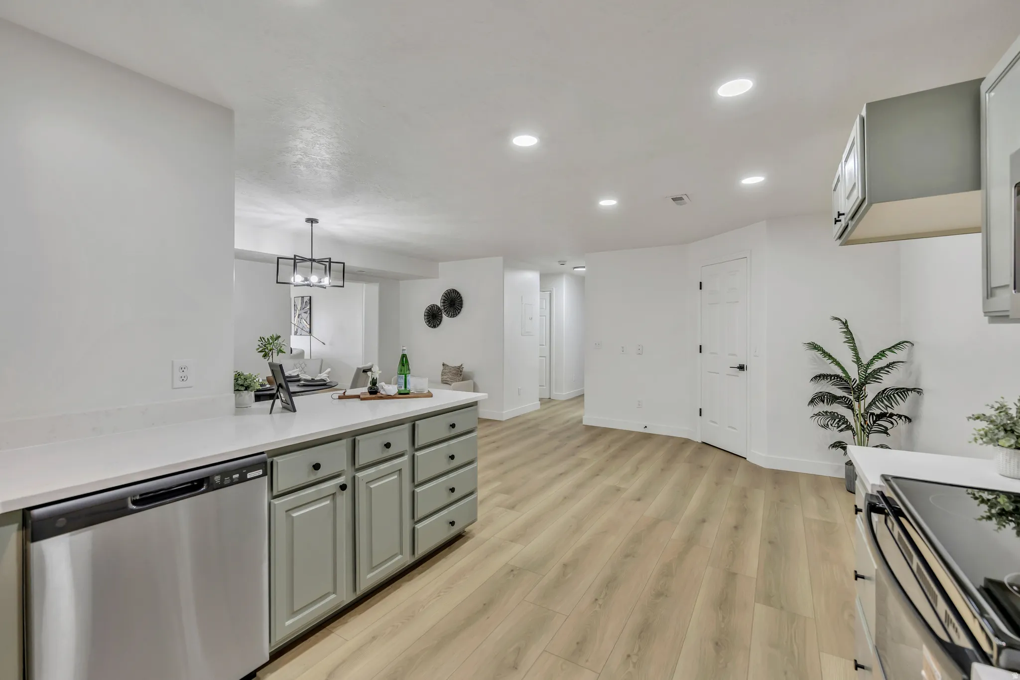 Kitchen featuring dishwasher, light wood-style flooring, light stone countertops, hanging light fixtures, and a peninsula