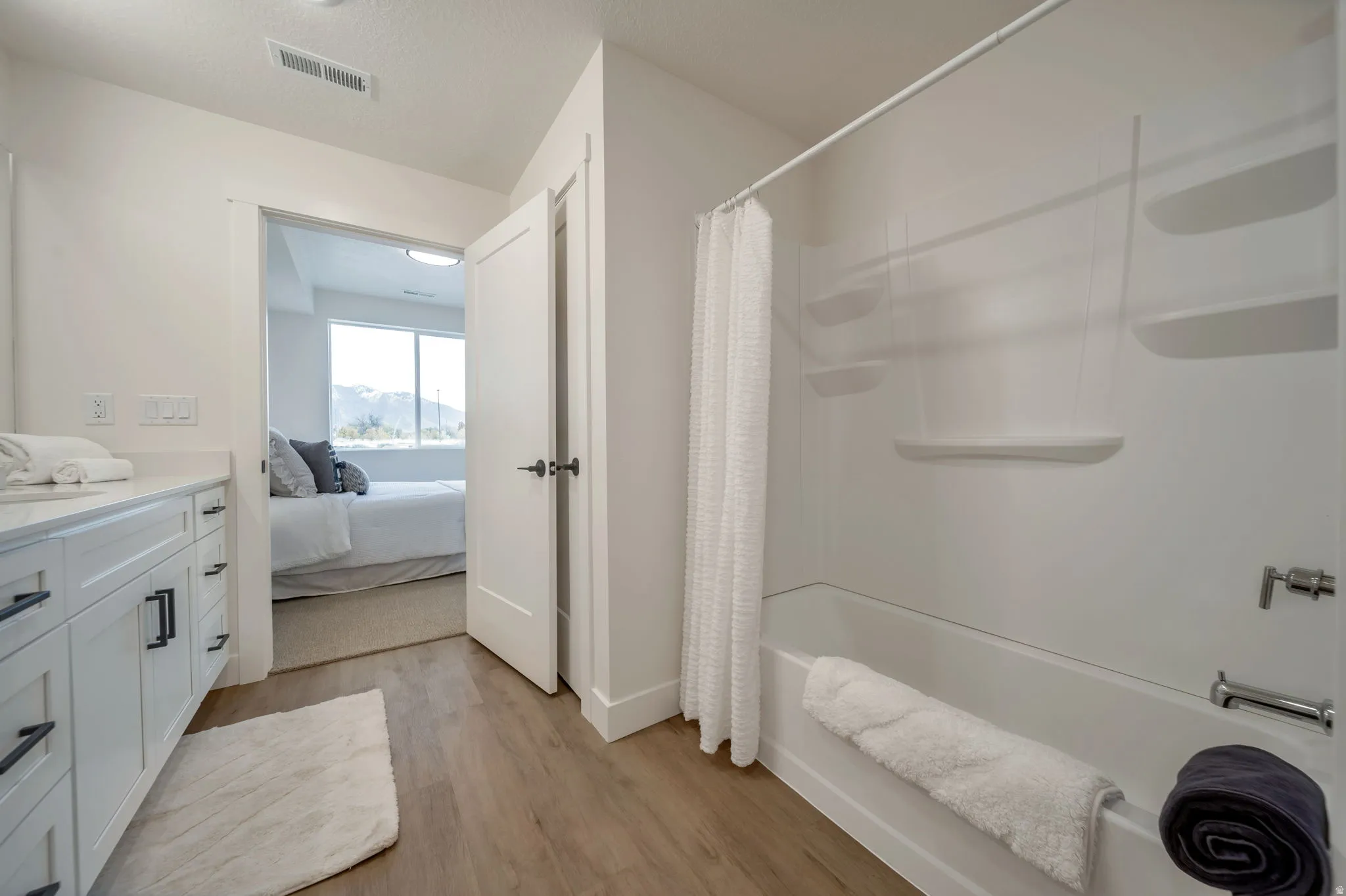 Bathroom with vanity, ensuite bath, light wood-style floors, and shower / bath combination with curtain