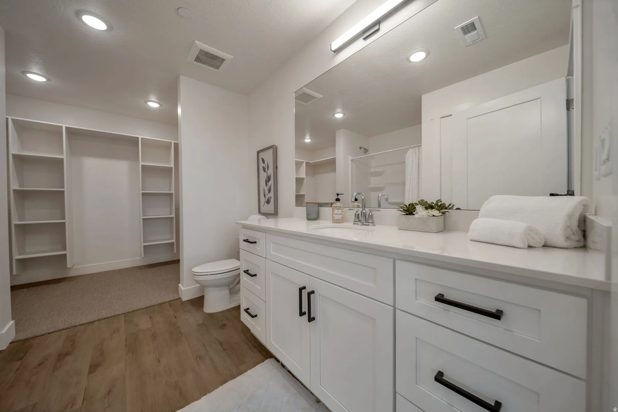 Bathroom with a shower with shower curtain, a walk in closet, light wood-style flooring, vanity, and recessed lighting