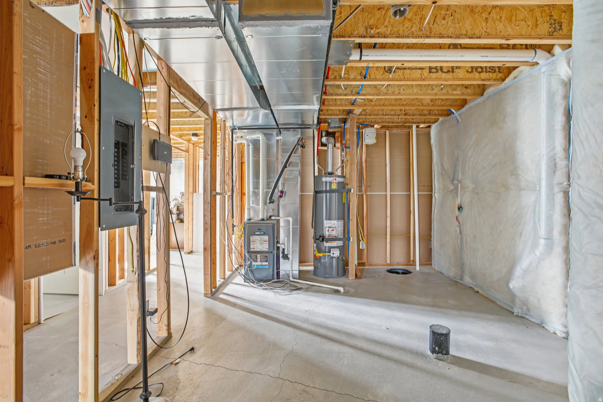 Unfinished basement featuring heating unit, electric panel, and water heater