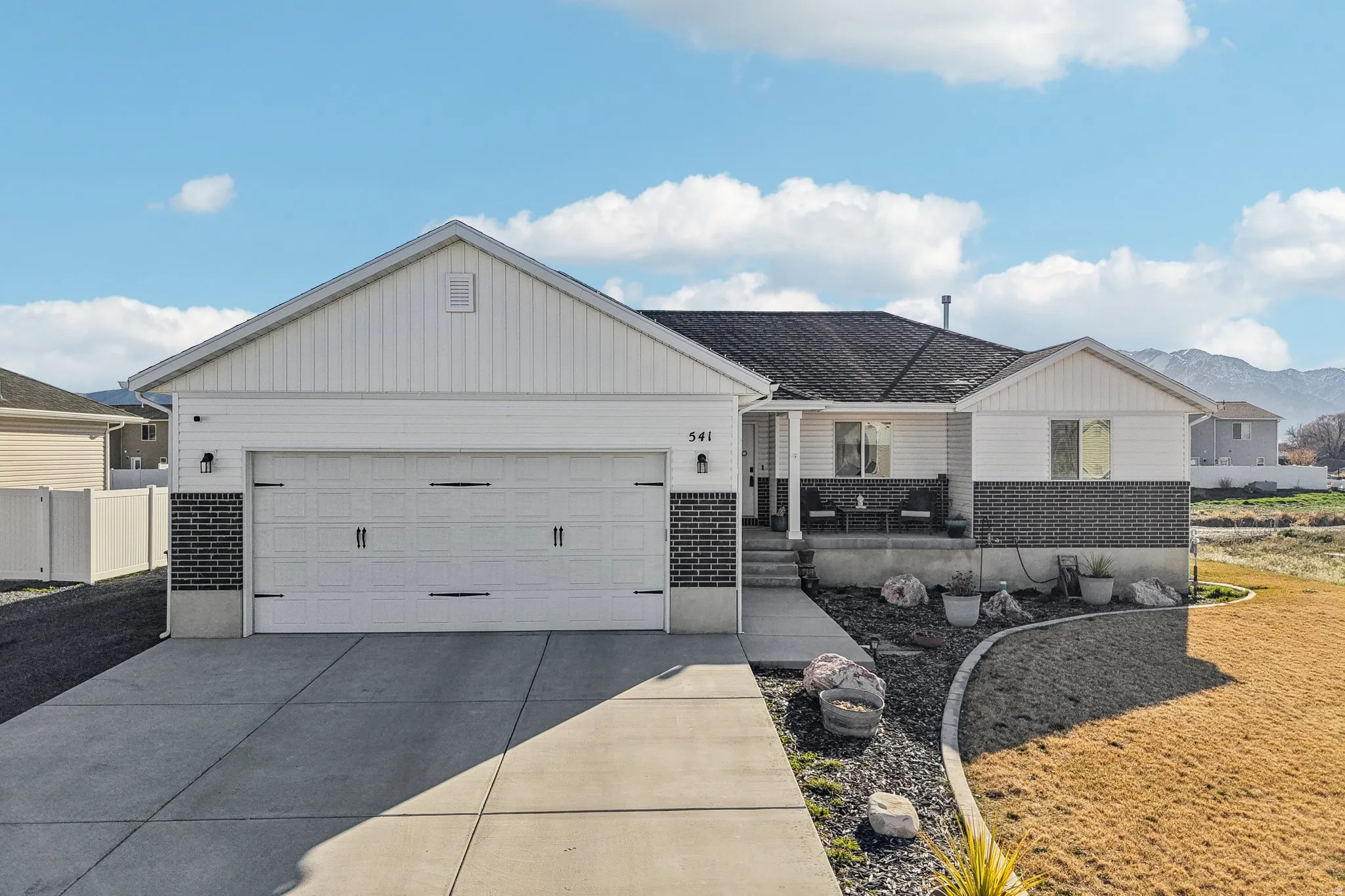Ranch-style home with brick siding, concrete driveway, a mountain view, and a garage