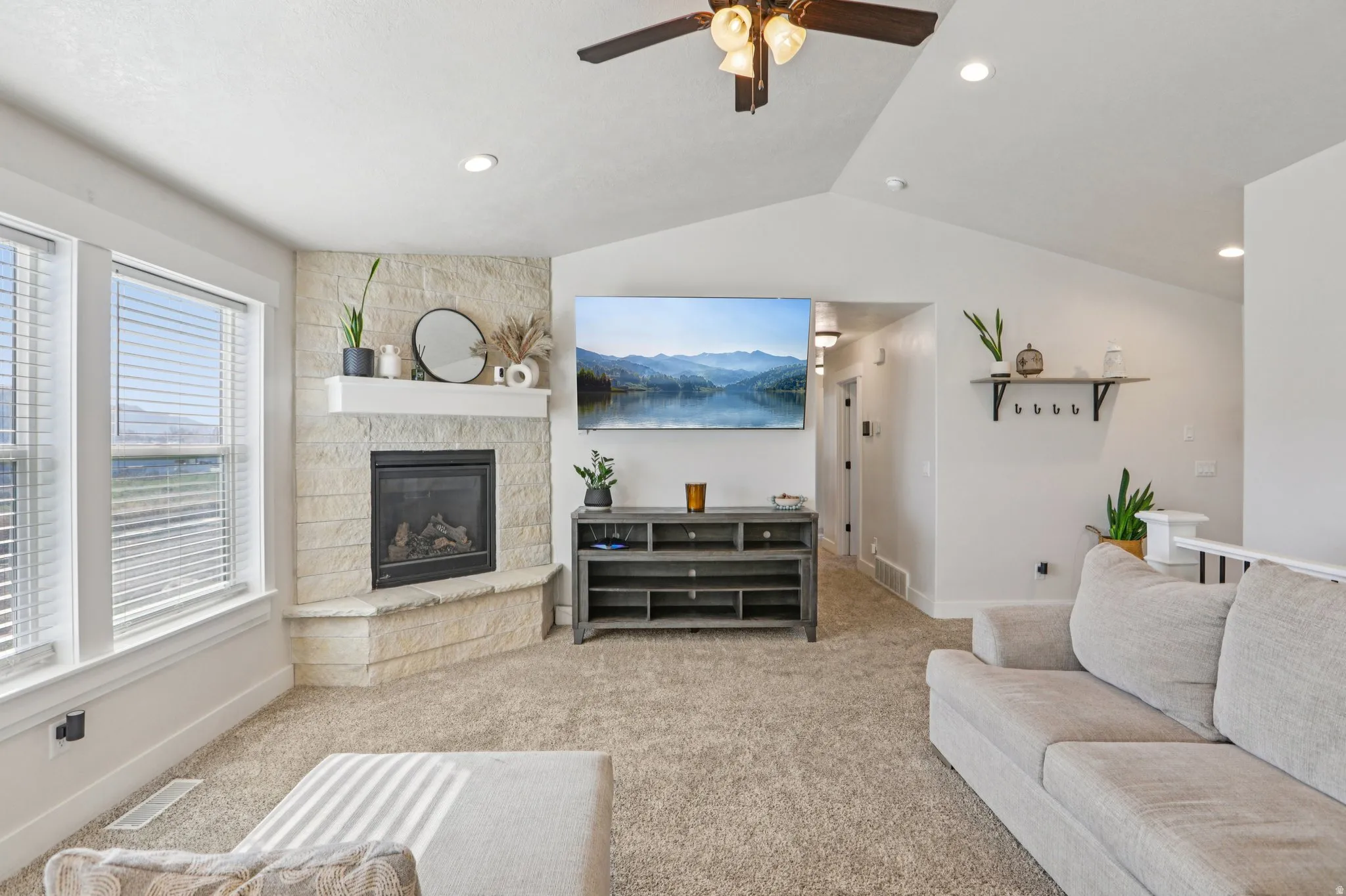 Carpeted living area with a ceiling fan and a fireplace