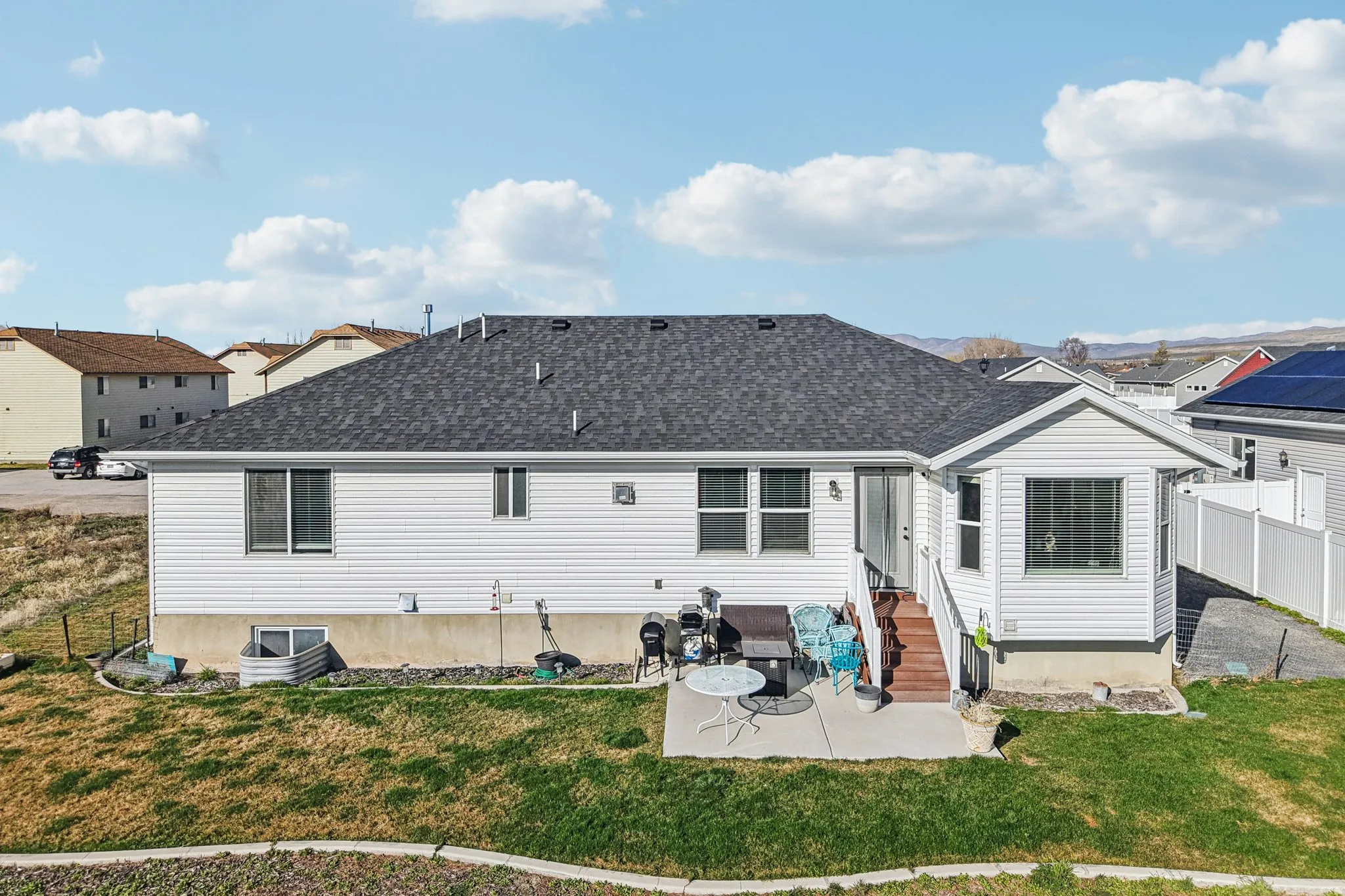 Rear view of property with a patio area, roof with shingles, entry steps, and a residential view