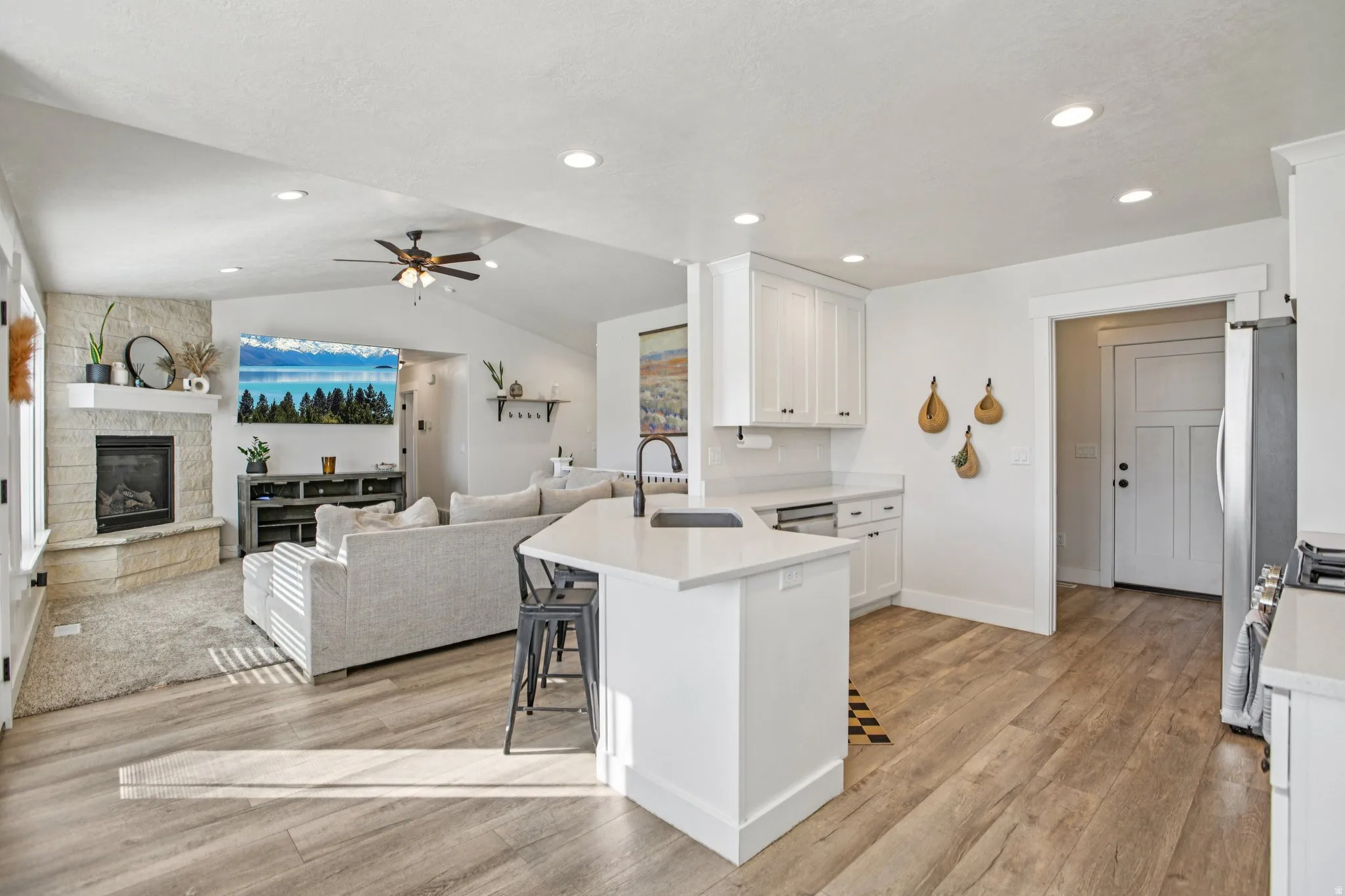 Kitchen with a breakfast bar area, open floor plan, white cabinetry, light wood finished floors, and vaulted ceiling