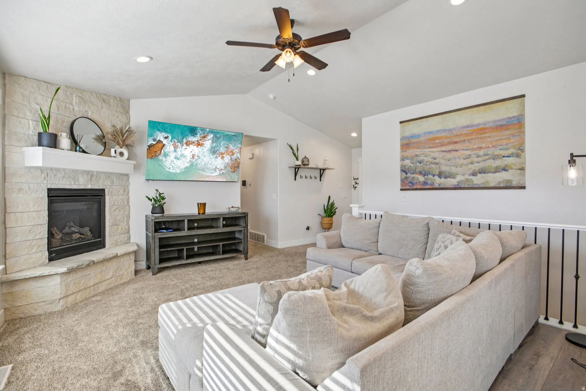 Living area with a ceiling fan, a fireplace, and carpet floors