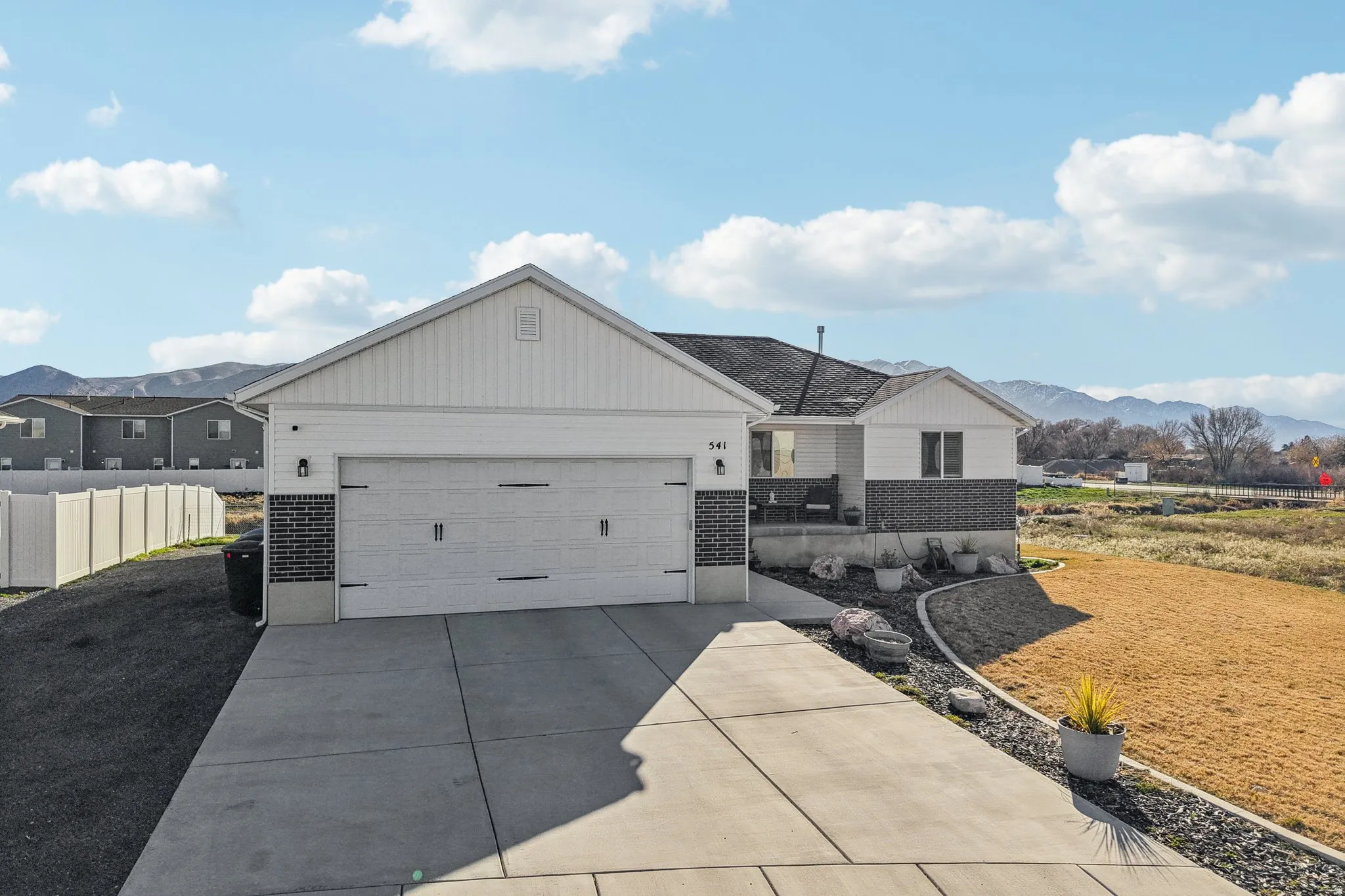 View of front of property featuring brick siding, a mountain view, concrete driveway, and an attached garage