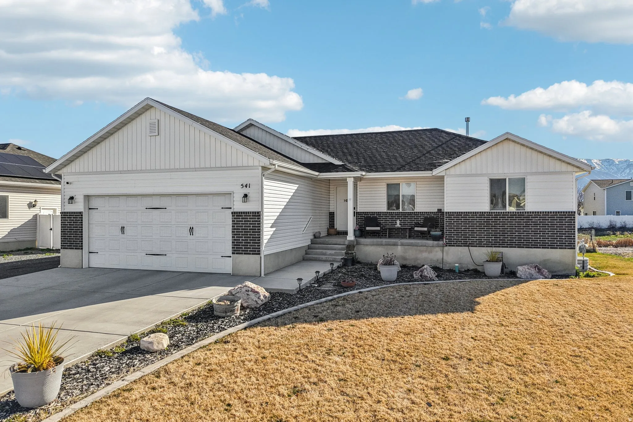 View of front facade featuring concrete driveway, an attached garage, brick siding, and covered porch