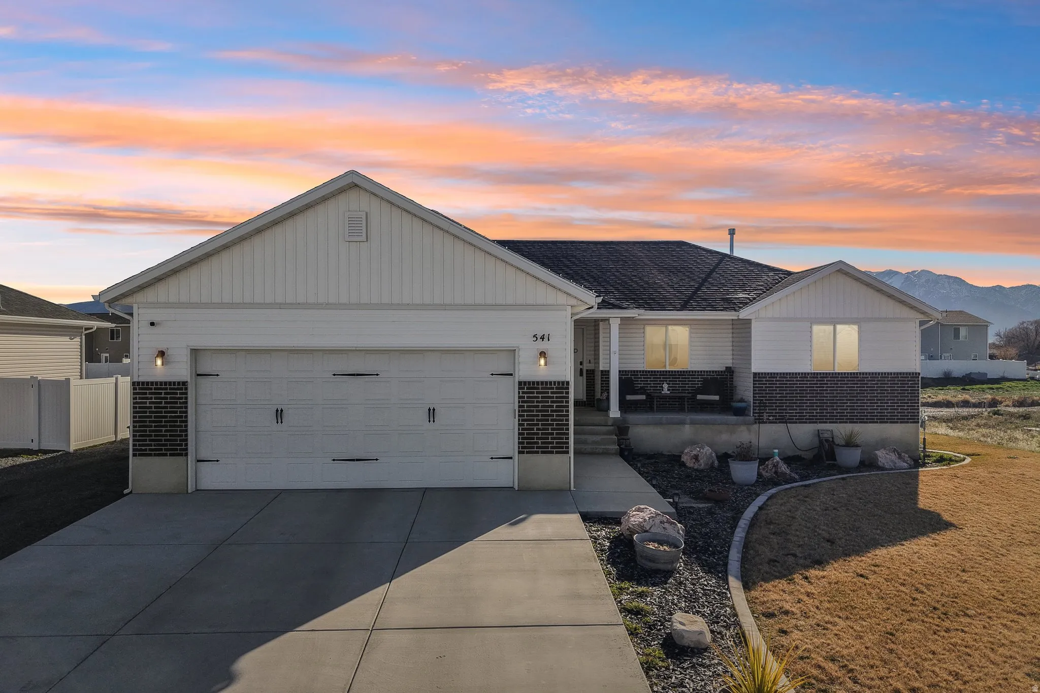 View of front of home with brick siding, driveway, an attached garage, and a porch
