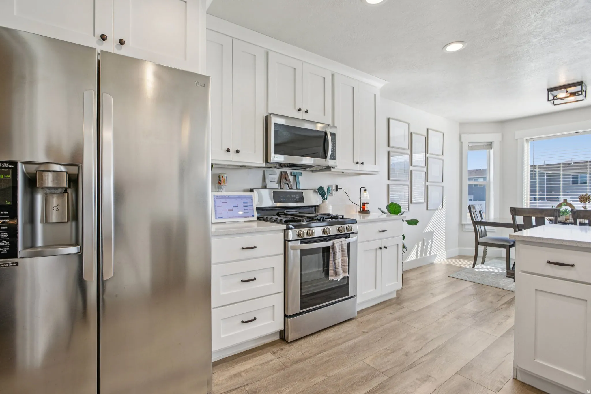 Kitchen with stainless steel appliances, white cabinets, light wood-type flooring, and recessed lighting