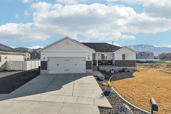 Single story home with concrete driveway, an attached garage, a mountain view, brick siding, and a porch