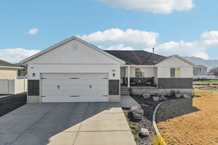 Ranch-style home with brick siding, concrete driveway, a mountain view, and a garage