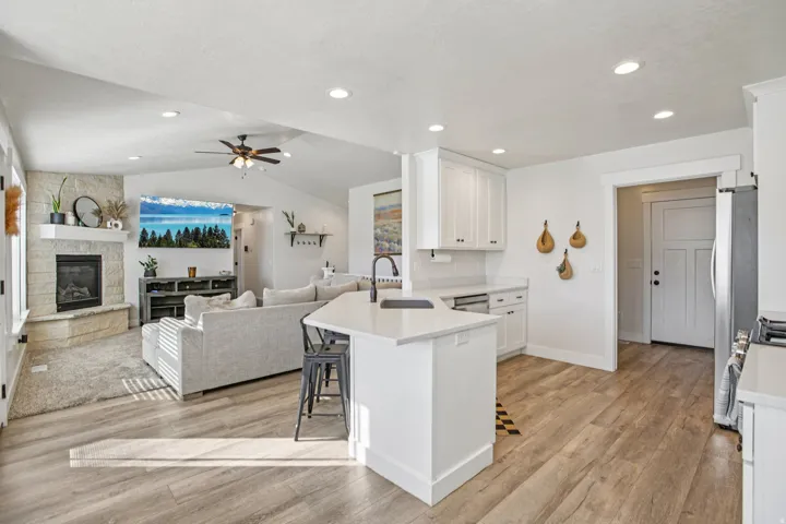 Kitchen with a breakfast bar area, open floor plan, white cabinetry, light wood finished floors, and vaulted ceiling