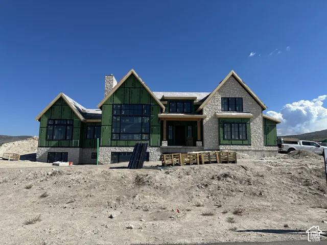 Custom-built residence featuring multi-gabled rooflines, stone masonry exterior, large multi-pane windows, and a prominent chimney stack