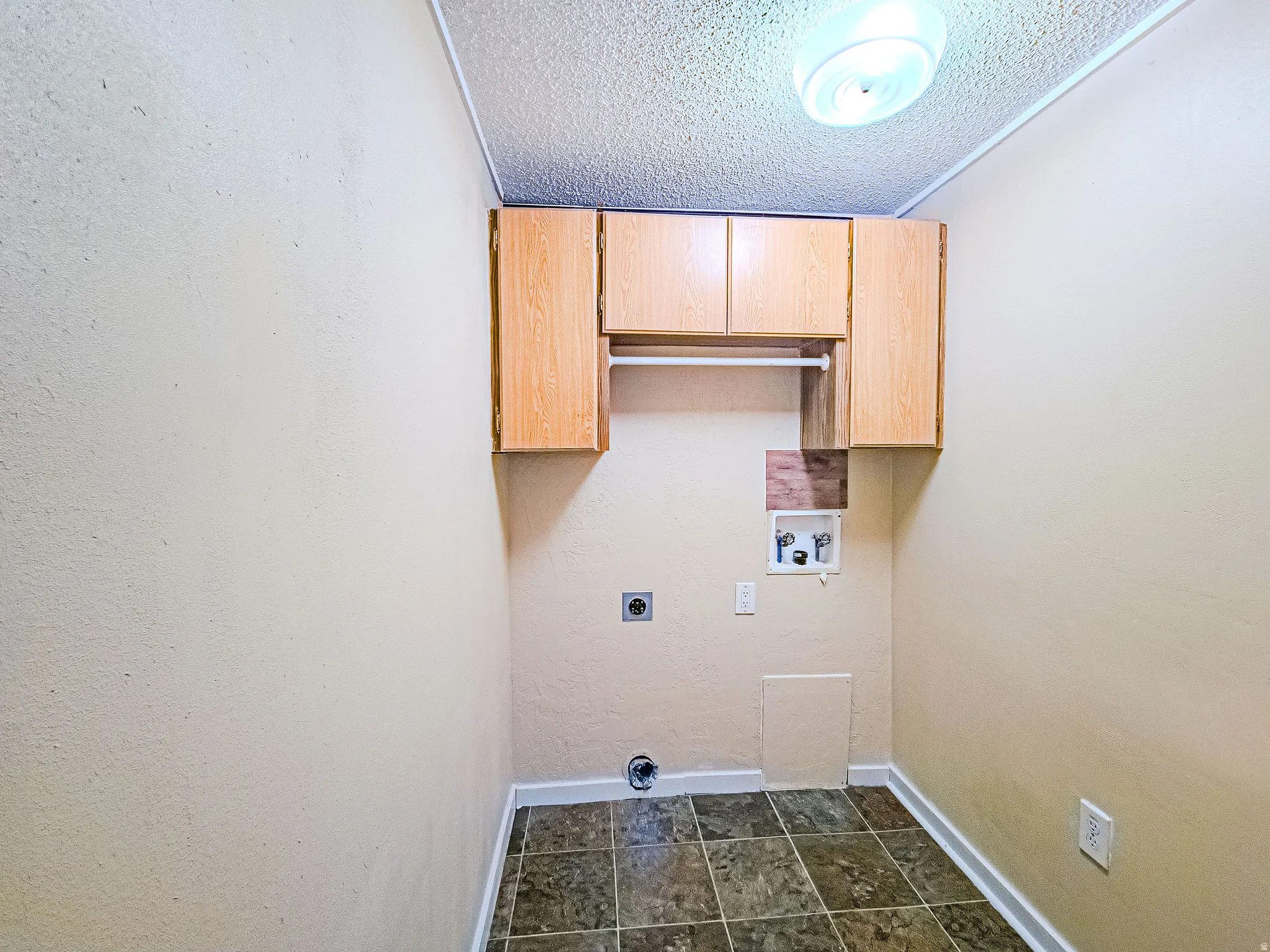 Laundry room with a textured ceiling, cabinet space, hookup for a washing machine, hookup for an electric dryer, and a textured wall