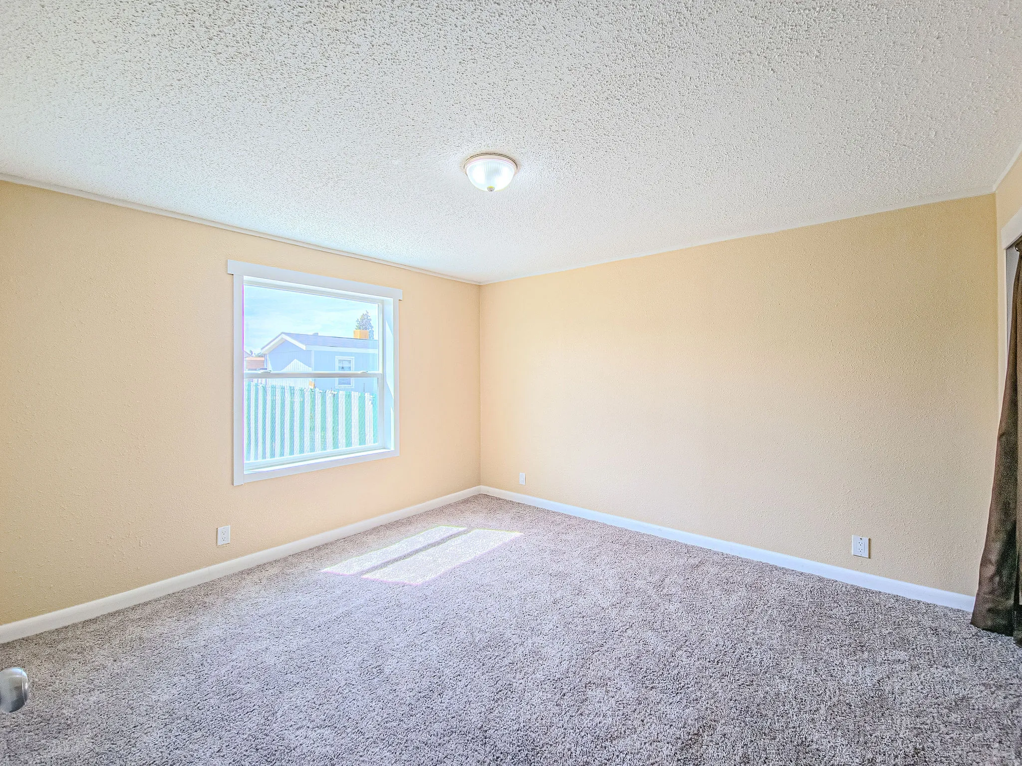 Carpeted spare room with a textured ceiling and baseboards