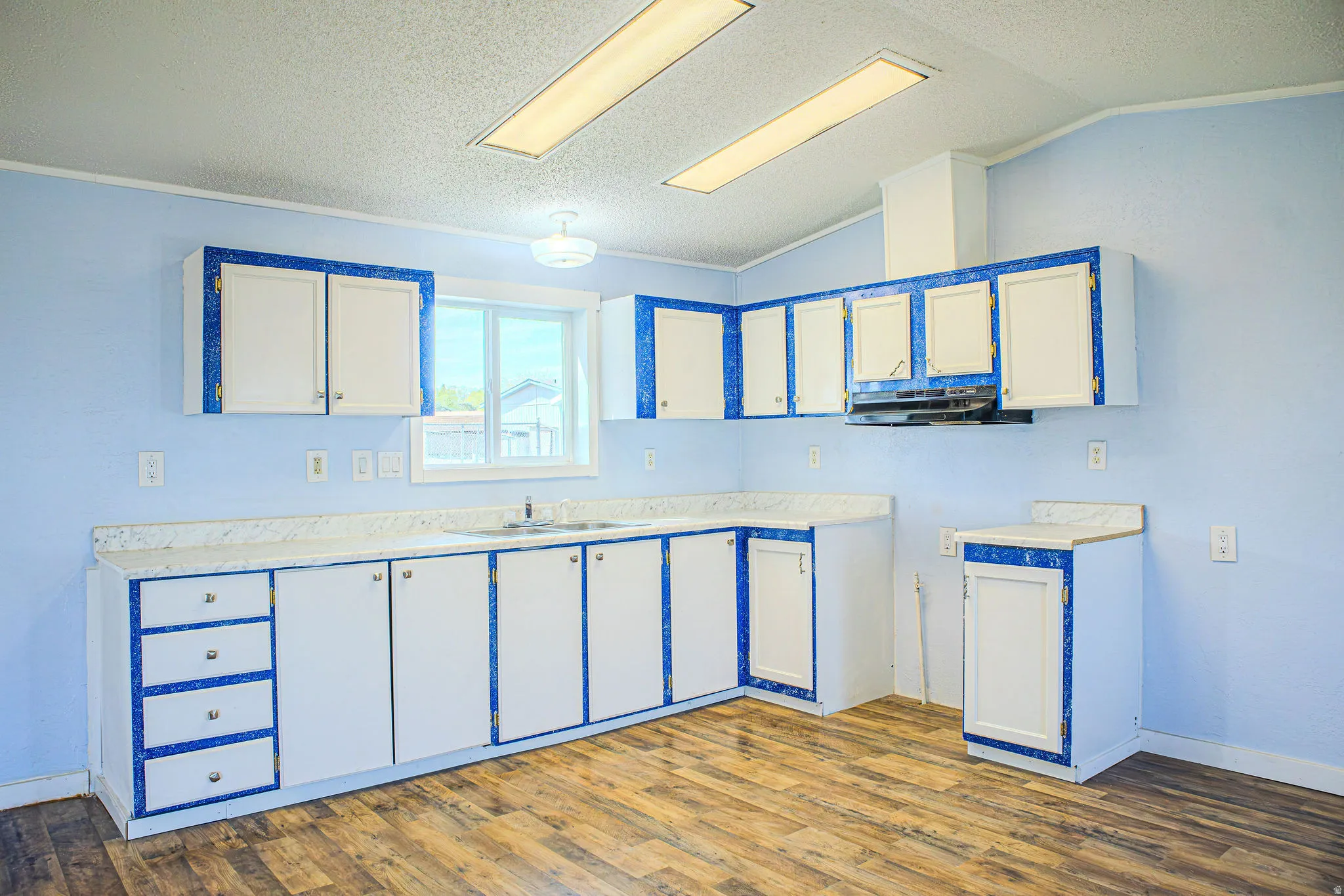 Kitchen featuring light countertops, white cabinetry, dark wood-style flooring, and ornamental molding