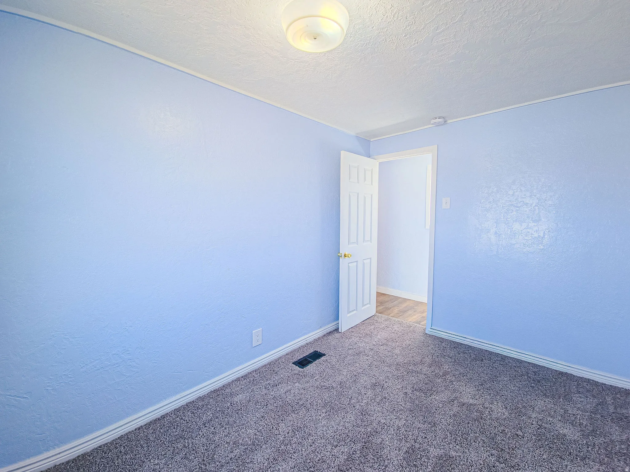 Empty room featuring a textured wall, carpet flooring, and a textured ceiling