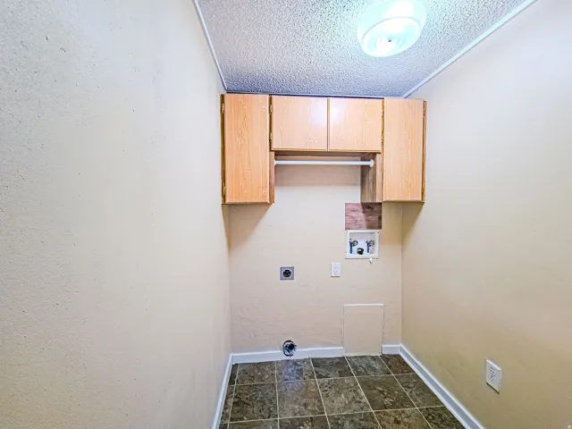 Laundry room with a textured ceiling, cabinet space, hookup for a washing machine, hookup for an electric dryer, and a textured wall
