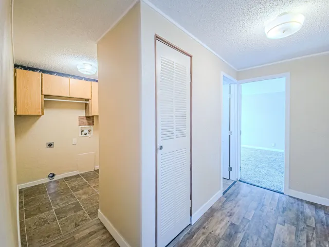 Laundry room featuring a textured ceiling, washer hookup, cabinet space, hookup for an electric dryer, and dark wood finished floors
