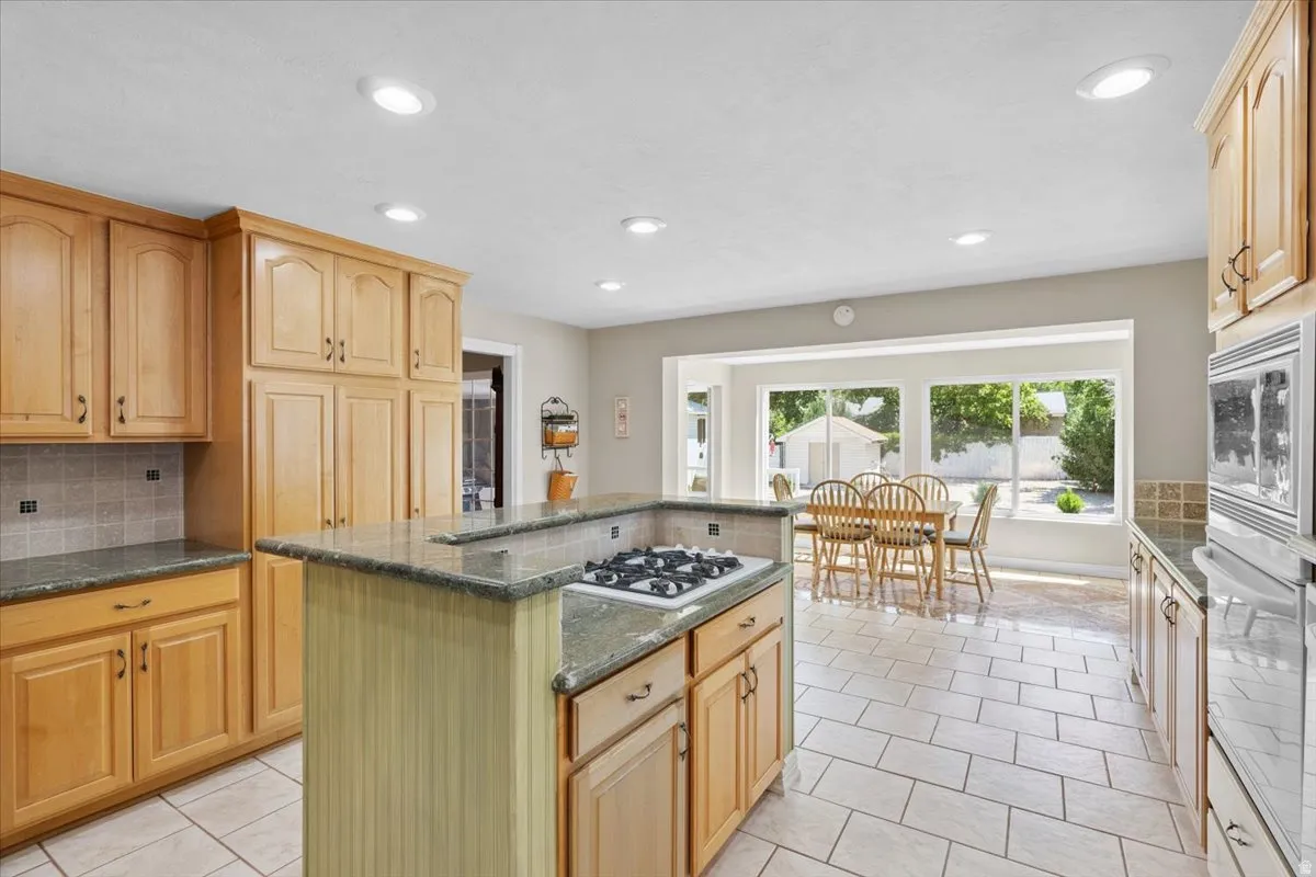 Kitchen featuring white appliances, a kitchen island, backsplash, light tile patterned flooring, and recessed lighting