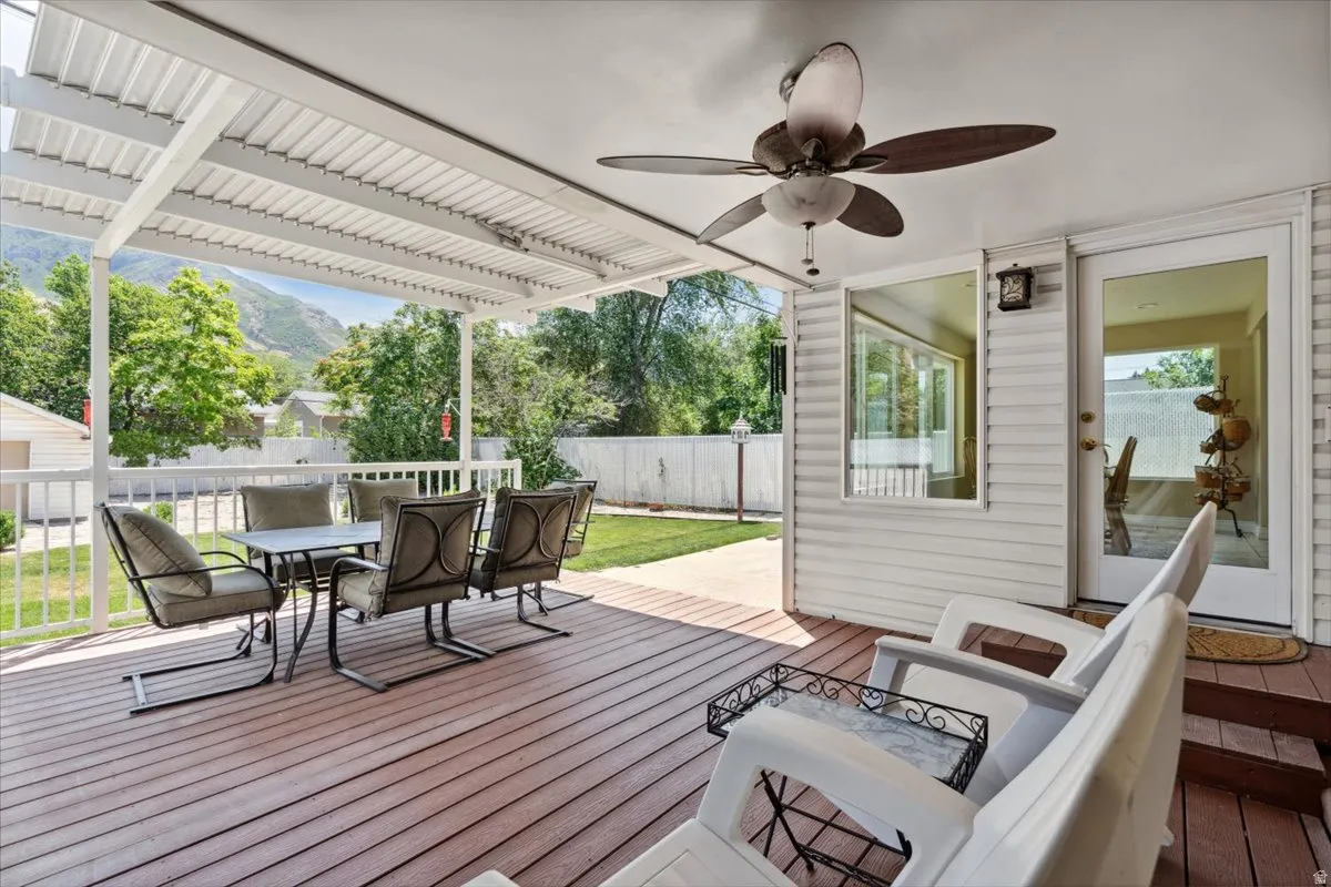 Deck featuring outdoor dining area, ceiling fan, and a fenced backyard