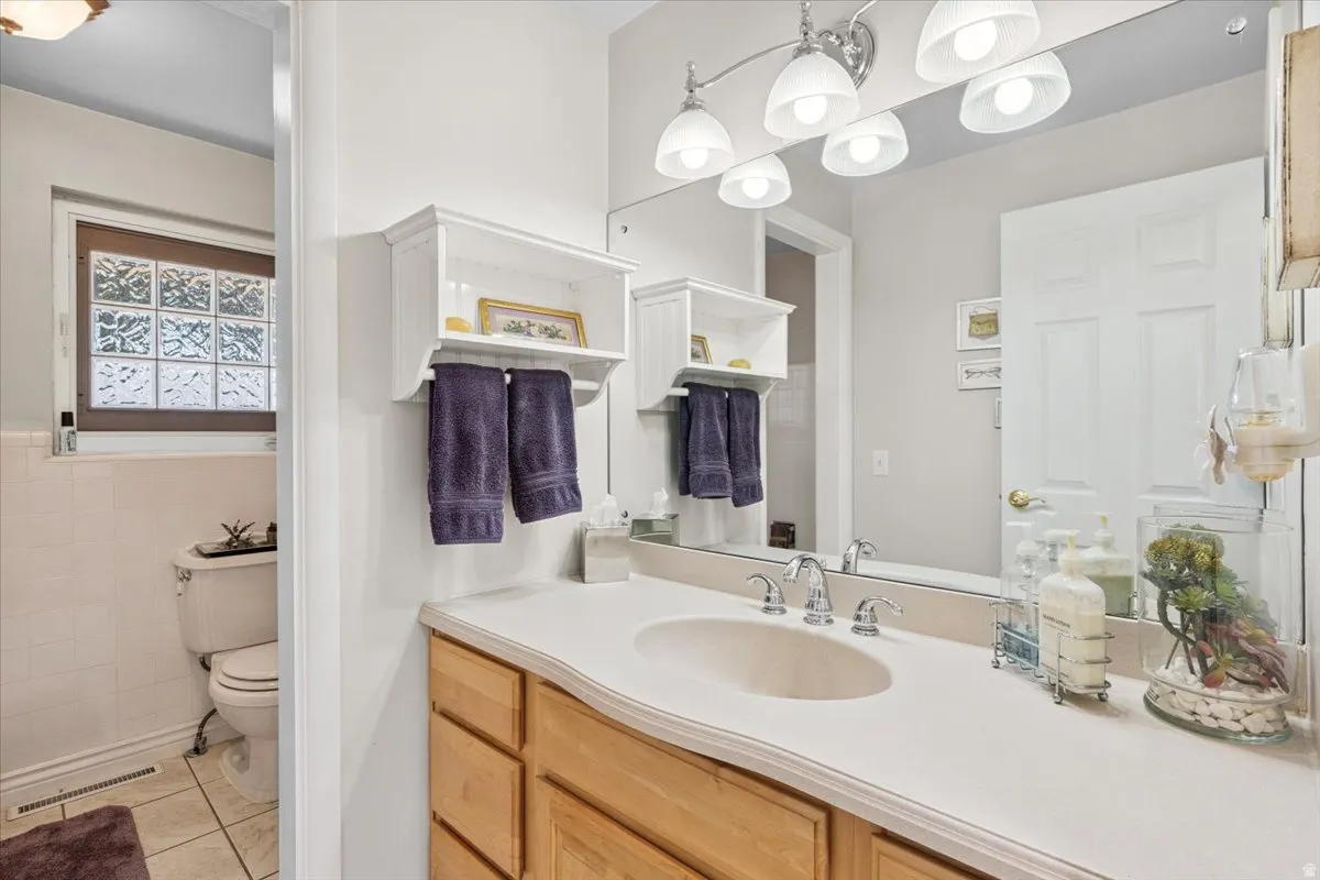 Bathroom with vanity, light tile patterned flooring, and tile walls