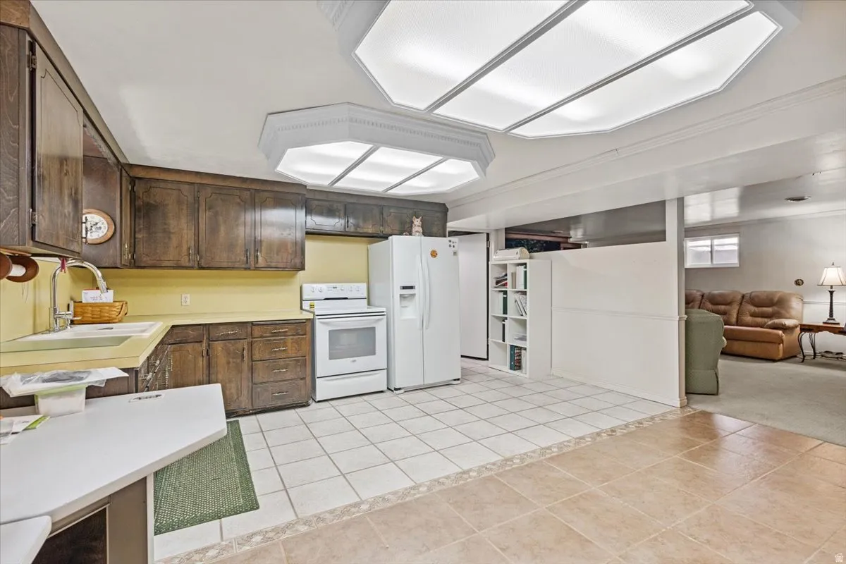 Second kitchen featuring light countertops, dark wood finish cabinets, white appliances, and open floor plan