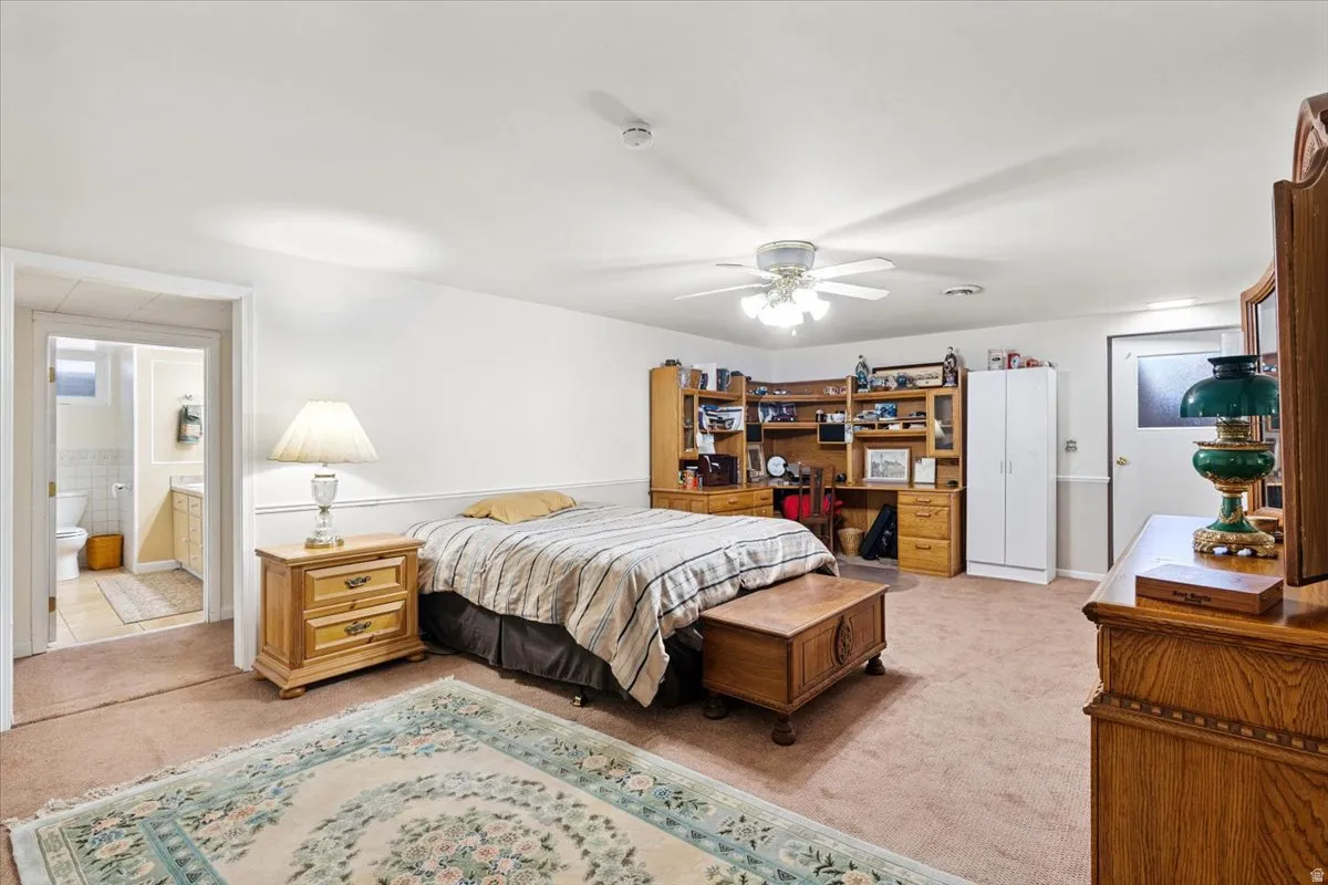 Bedroom featuring light carpet, ceiling fan, and connected bathroom