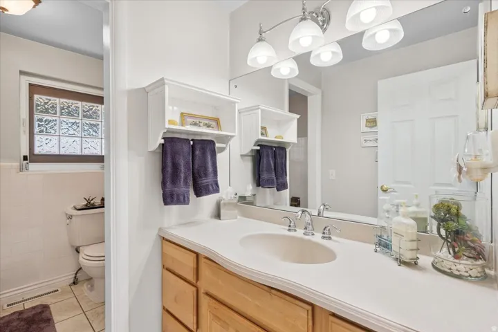 Bathroom with vanity, light tile patterned flooring, and tile walls