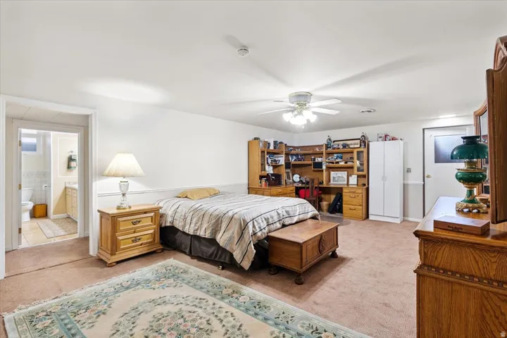 Bedroom featuring light carpet, ceiling fan, and connected bathroom