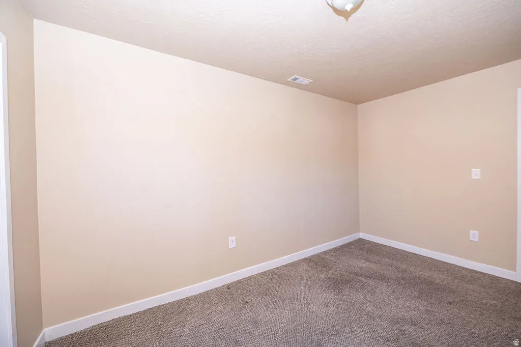 Spare room featuring carpet flooring and a textured ceiling
