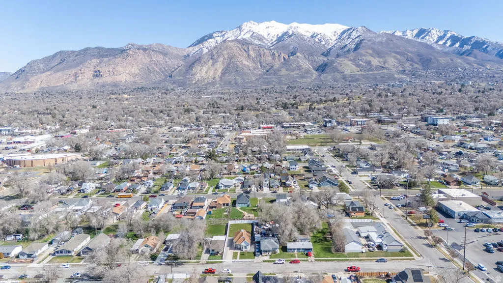 Aerial view of property and surrounding area featuring a mountainous background and nearby suburban area