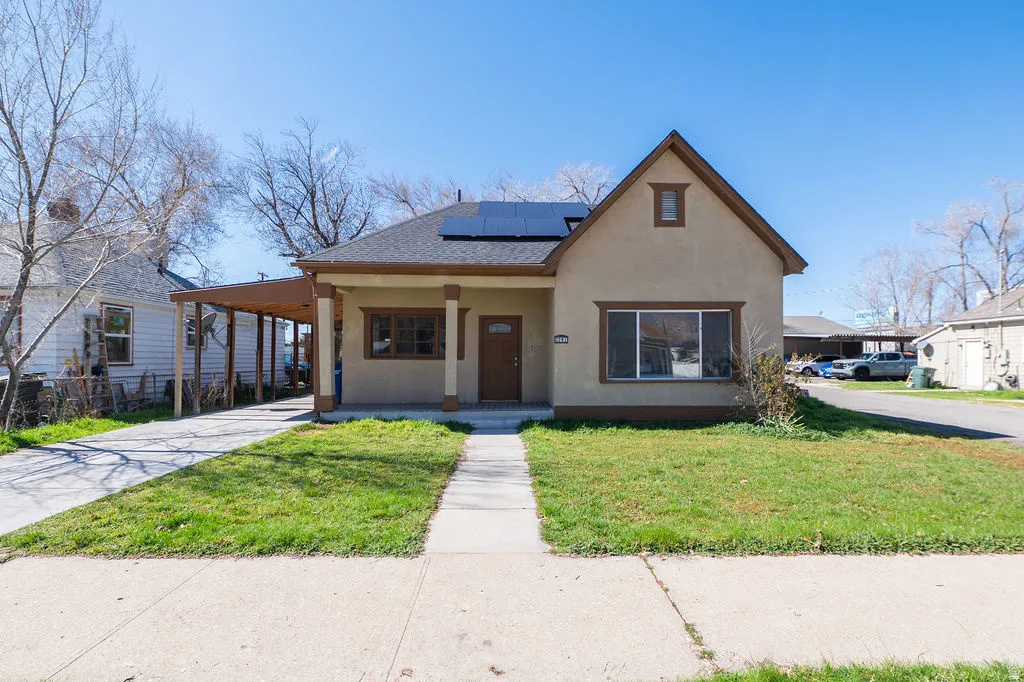 View of front of house with a porch, a carport, roof mounted solar panels, stucco siding, and concrete driveway