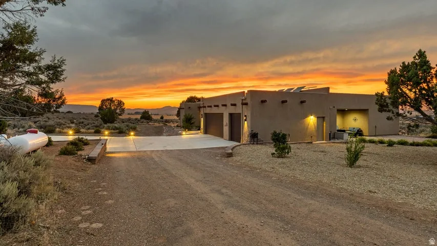 Pueblo-style house with concrete driveway, an attached garage, and stucco siding