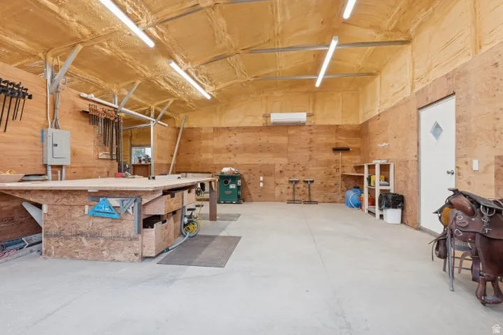 Garage featuring a workshop area, wood walls, and electric panel
