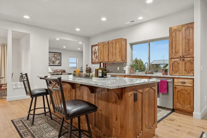 Kitchen with wood finish cabinetry, light stone countertops, light wood finished floors, tasteful backsplash, and a center island