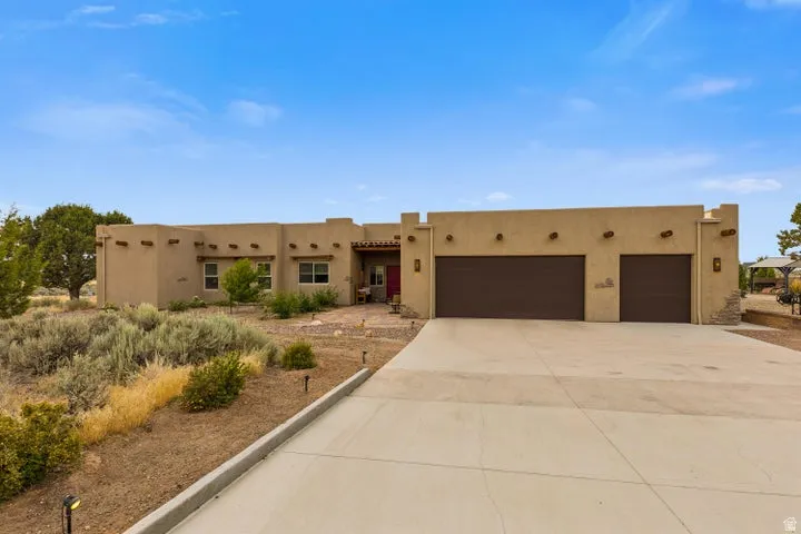 Adobe home with an attached garage, stucco siding, and driveway