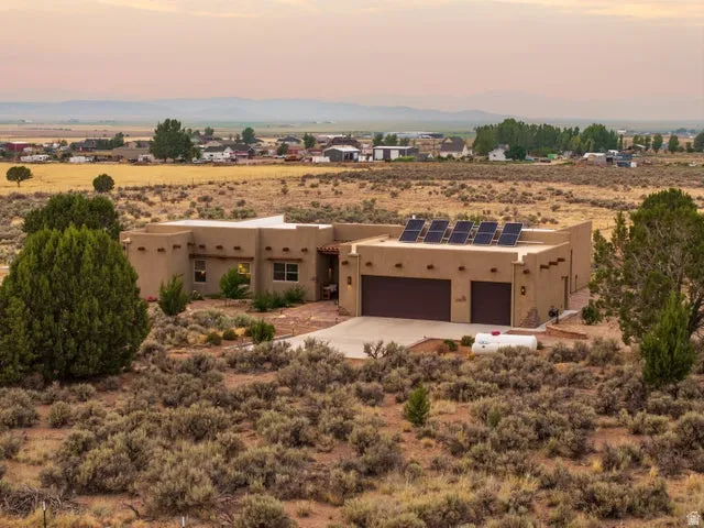 Southwest-style home featuring solar panels, stucco siding, view of desert landscape, and a view of rural / pastoral area