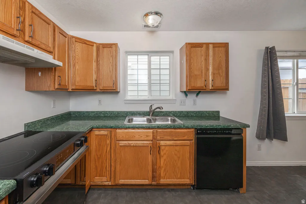 Kitchen featuring black appliances, dark countertops, wood finish cabinets, and a textured ceiling