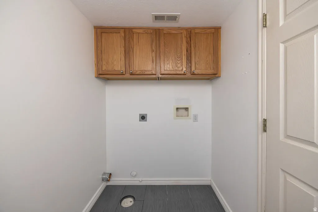 Laundry area with cabinet space, washer hookup, a textured ceiling, and electric dryer hookup