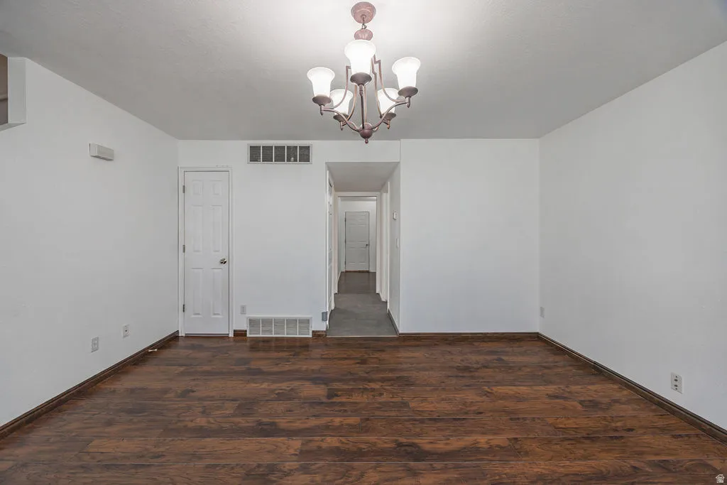 Unfurnished dining area with hanging lights and dark wood-type flooring