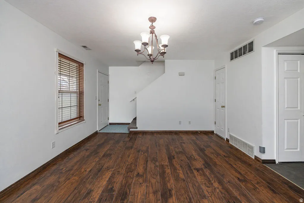 Unfurnished dining area with a chandelier and dark wood-style floors