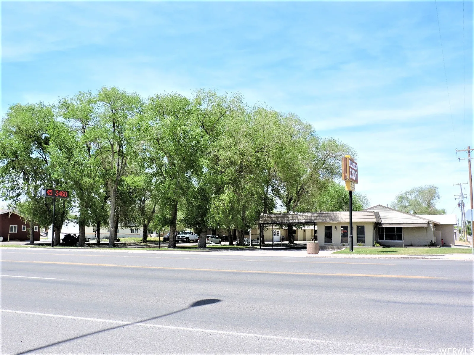 View of asphalt street featuring traffic signs, sidewalks, and curbs